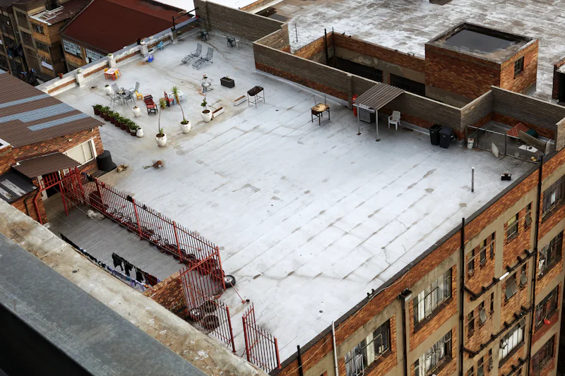 Flat commercial roof from above, with snow on the membrane and rooftop units