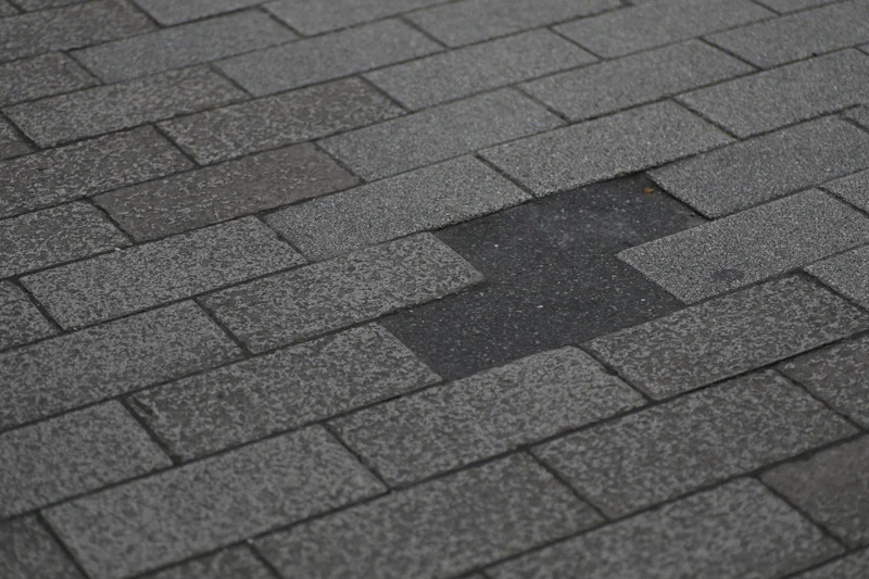 Asphalt shingle roof with a patch of shingles torn away
